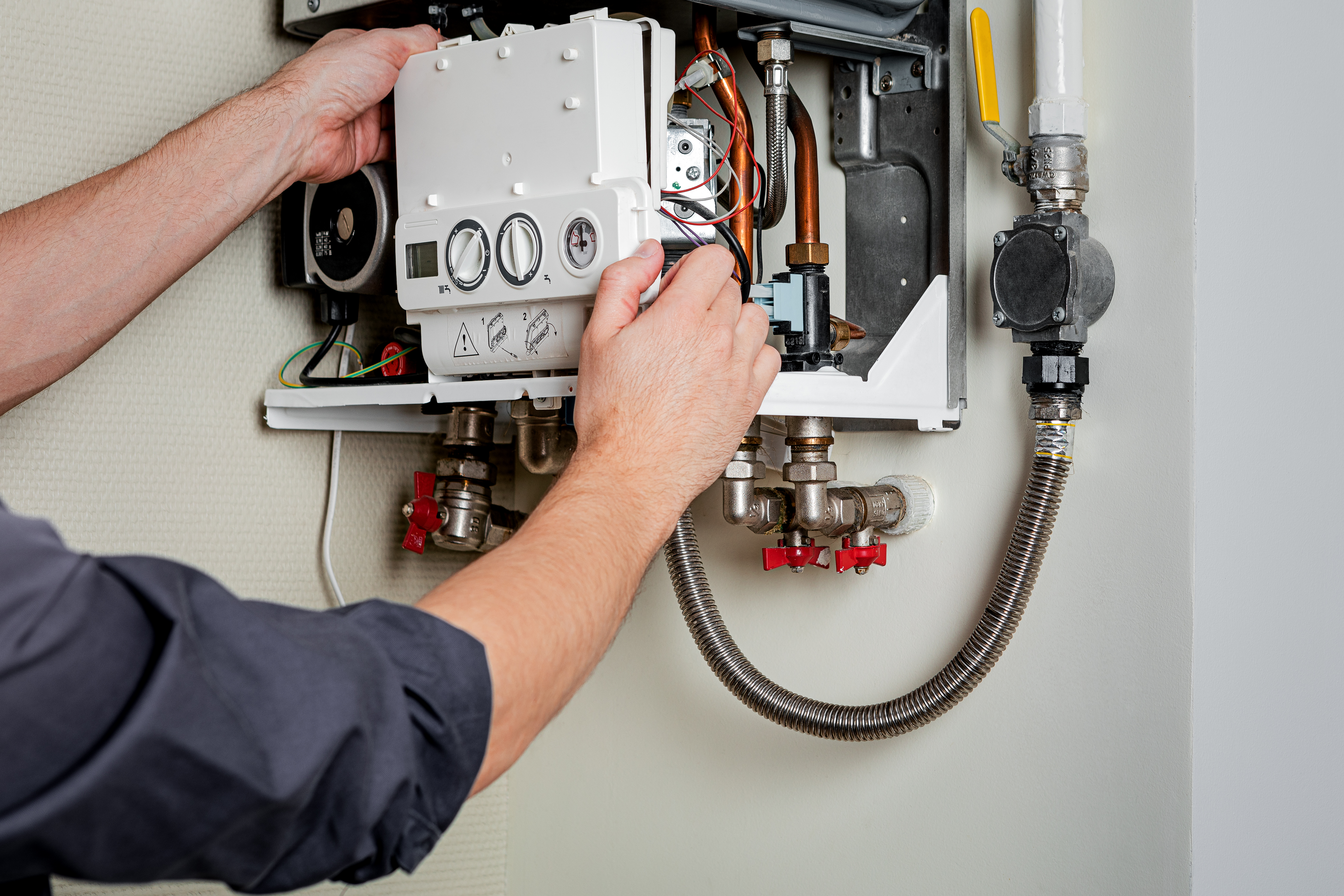 Plumber servicing a water heater's controls and valves